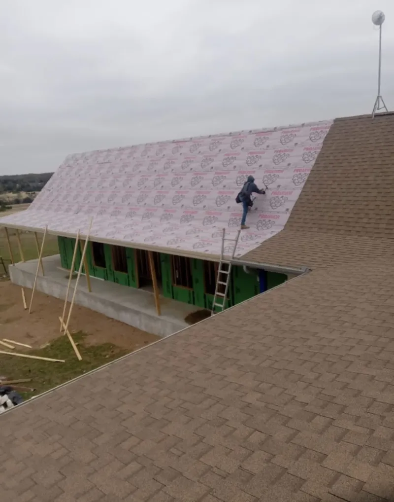 Worker preparing underlayment for a metal roof installation in Greenwood Village